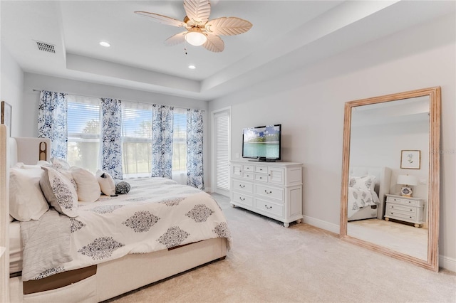 carpeted bedroom featuring a raised ceiling and ceiling fan