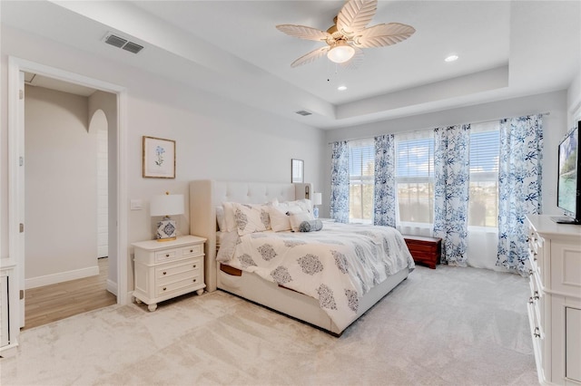 carpeted bedroom with a tray ceiling and ceiling fan