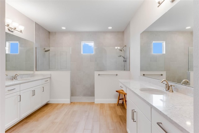 bathroom with a tile shower, vanity, and hardwood / wood-style flooring