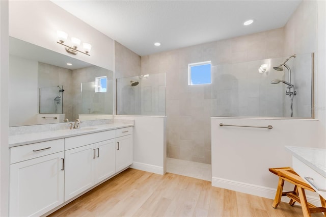 bathroom with a tile shower, vanity, and hardwood / wood-style flooring