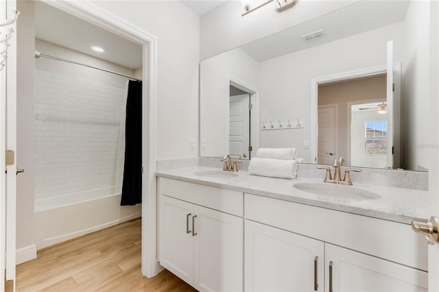 bathroom with wood-type flooring, vanity, shower / tub combo with curtain, and ceiling fan