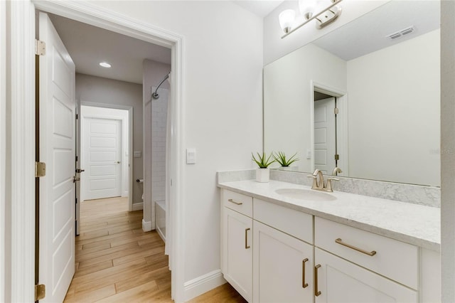 bathroom with hardwood / wood-style floors, vanity, and  shower combination