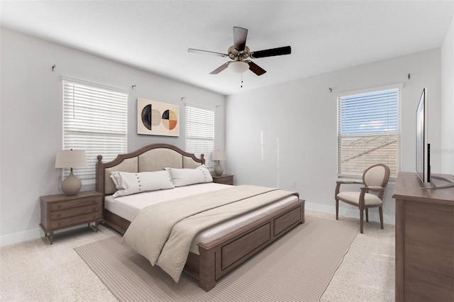 bedroom with ceiling fan, light carpet, and multiple windows