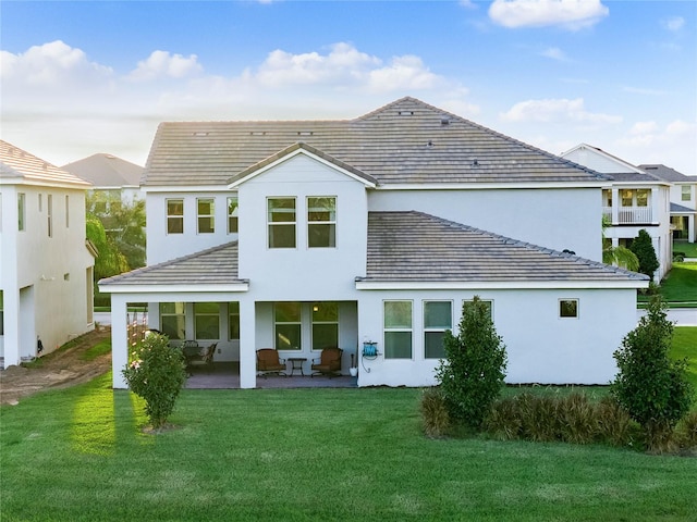 rear view of house featuring a patio area and a lawn