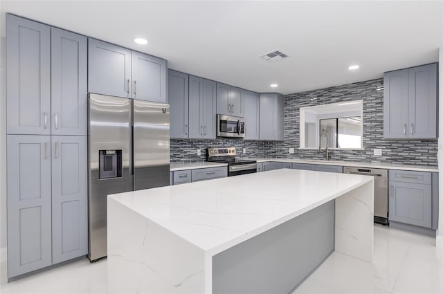 kitchen featuring backsplash, a center island, light stone counters, and stainless steel appliances