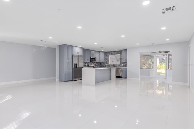 kitchen with backsplash, sink, gray cabinets, appliances with stainless steel finishes, and a kitchen island