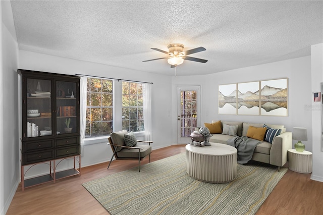 living room with ceiling fan, a textured ceiling, and hardwood / wood-style flooring