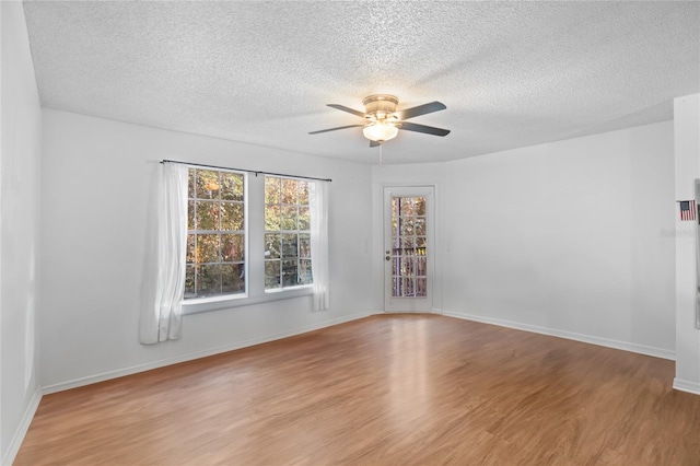 empty room with ceiling fan, a textured ceiling, and light wood-type flooring