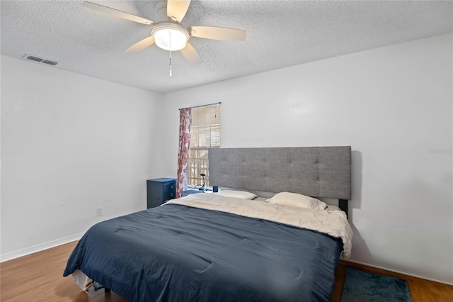 bedroom with ceiling fan, a textured ceiling, and hardwood / wood-style flooring