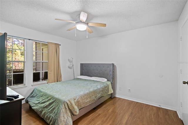 bedroom featuring ceiling fan, hardwood / wood-style floors, and a textured ceiling