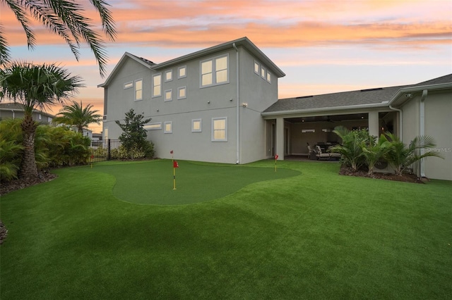 back house at dusk featuring a yard