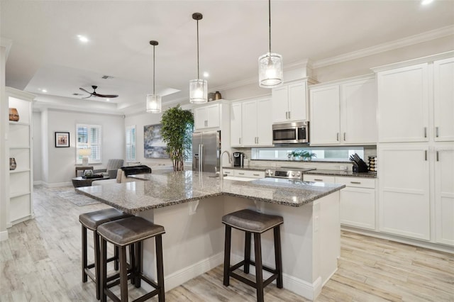 kitchen featuring hanging light fixtures, a kitchen island with sink, and appliances with stainless steel finishes