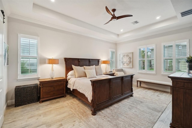 bedroom with ceiling fan, a raised ceiling, light wood-type flooring, and ornamental molding