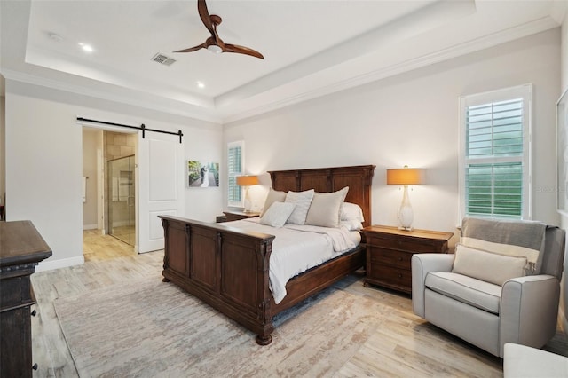 bedroom featuring multiple windows, a barn door, a raised ceiling, and ceiling fan