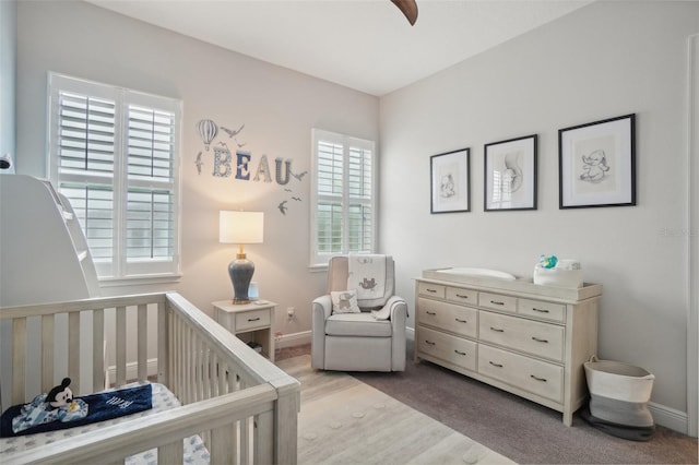 bedroom with carpet flooring, ceiling fan, and a nursery area