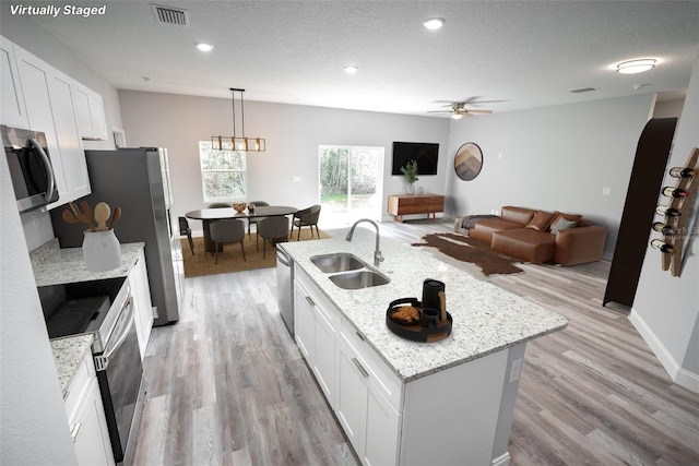 kitchen featuring pendant lighting, white cabinets, sink, an island with sink, and appliances with stainless steel finishes