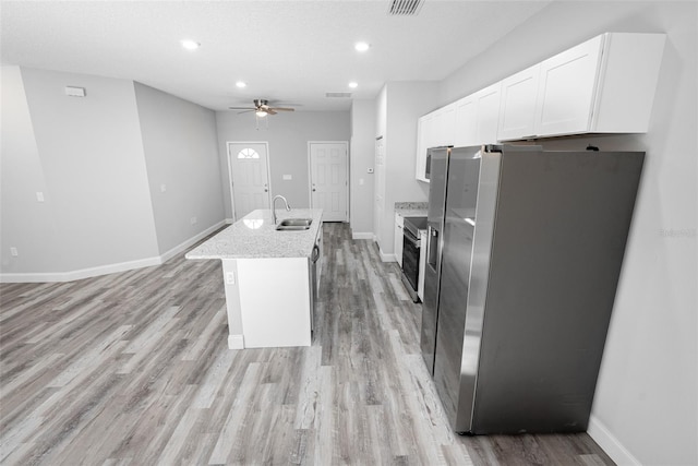 kitchen featuring white cabinetry, sink, stainless steel appliances, light hardwood / wood-style flooring, and a center island with sink