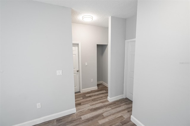 hall featuring light wood-type flooring and a textured ceiling