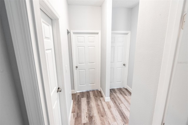 hallway with a textured ceiling and light wood-type flooring