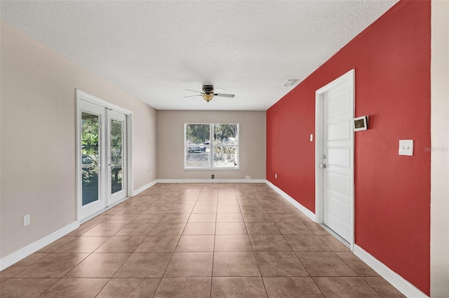 tiled empty room with ceiling fan and a textured ceiling