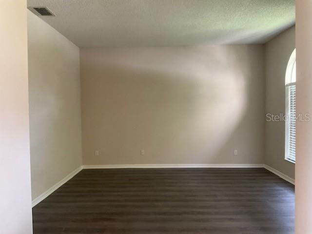 empty room with a textured ceiling and dark wood-type flooring