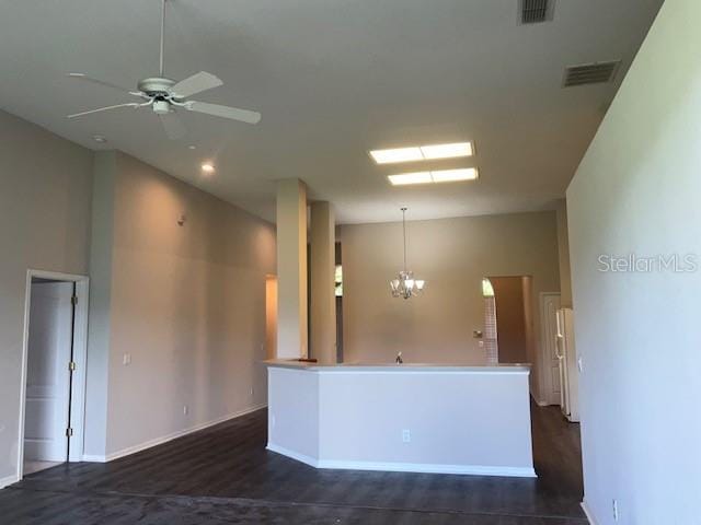 kitchen with decorative light fixtures, ceiling fan with notable chandelier, and dark wood-type flooring