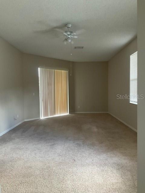 carpeted empty room with ceiling fan and a textured ceiling