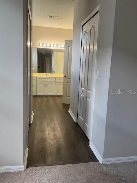 corridor featuring dark hardwood / wood-style flooring and a textured ceiling