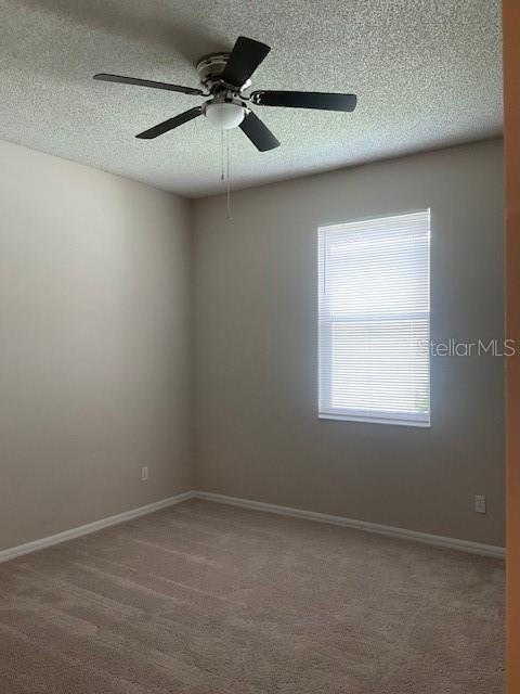 unfurnished room featuring carpet, a textured ceiling, and ceiling fan