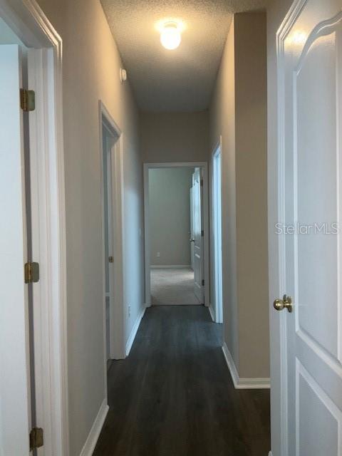 hall with dark hardwood / wood-style flooring and a textured ceiling