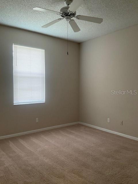 carpeted empty room with a textured ceiling and ceiling fan