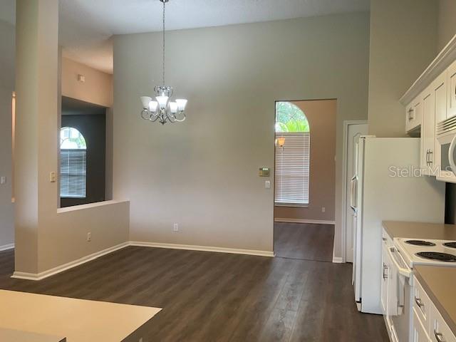 kitchen with dark wood-type flooring, white cabinets, white electric stove, decorative light fixtures, and a notable chandelier