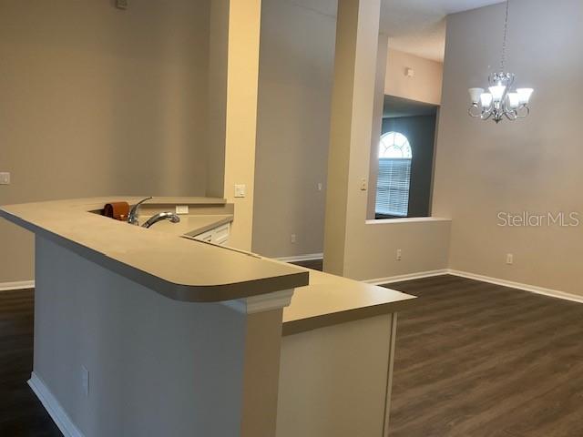 kitchen featuring kitchen peninsula, dark hardwood / wood-style flooring, a chandelier, and hanging light fixtures