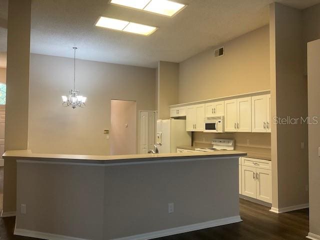 kitchen featuring white appliances, white cabinets, decorative light fixtures, dark hardwood / wood-style flooring, and a chandelier