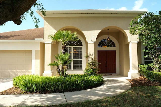 entrance to property with an attached garage and stucco siding