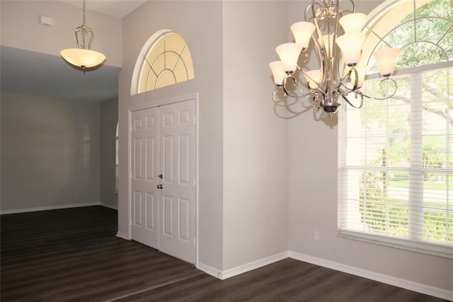interior space featuring a chandelier, baseboards, and dark wood finished floors