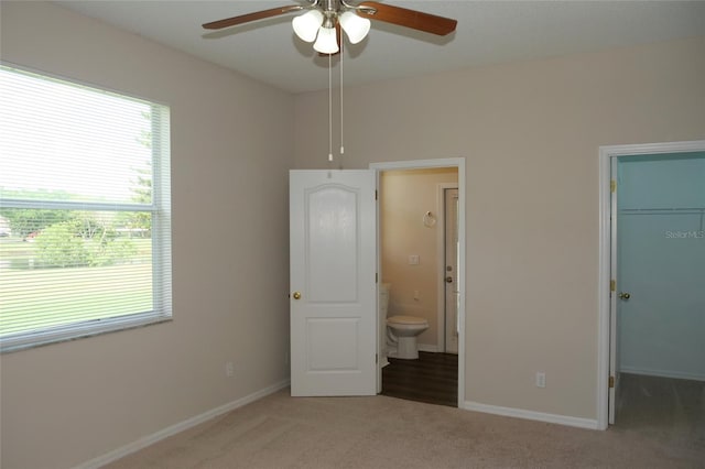unfurnished bedroom with a closet, baseboards, a spacious closet, connected bathroom, and carpet floors