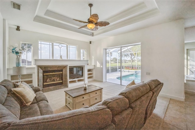 living room featuring a tray ceiling, ceiling fan, and ornamental molding