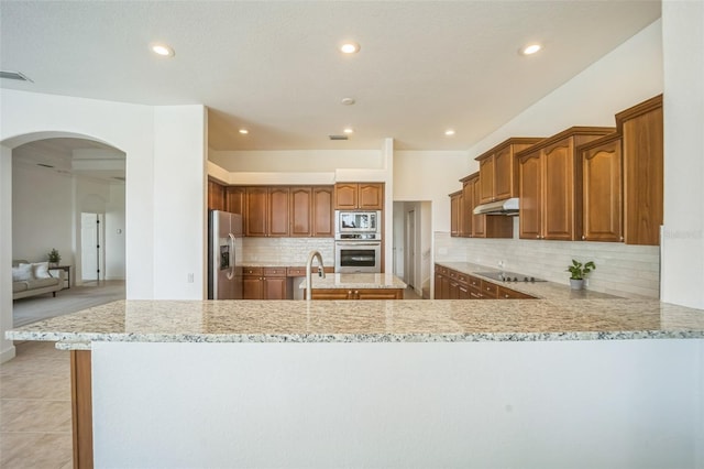 kitchen featuring kitchen peninsula, light stone countertops, and appliances with stainless steel finishes