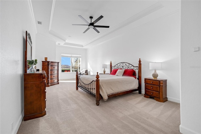 carpeted bedroom with a tray ceiling, ceiling fan, and crown molding