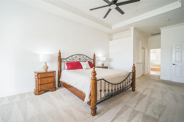 carpeted bedroom featuring a raised ceiling, ensuite bath, ceiling fan, and ornamental molding