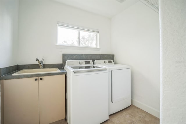 clothes washing area featuring washer and clothes dryer, cabinets, light tile patterned floors, and sink