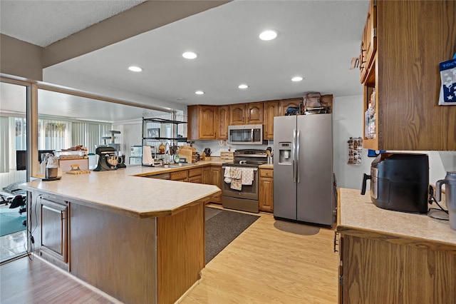 kitchen featuring light hardwood / wood-style floors, kitchen peninsula, sink, and appliances with stainless steel finishes