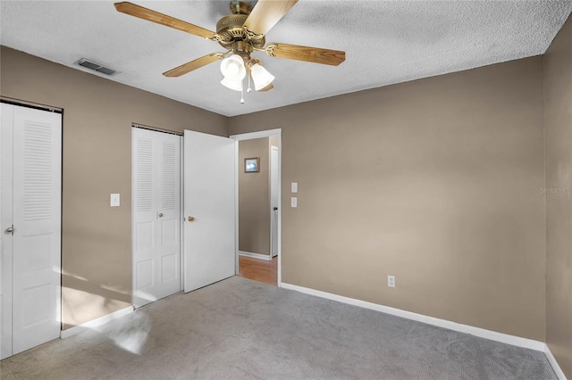 unfurnished bedroom featuring light carpet, a textured ceiling, and ceiling fan