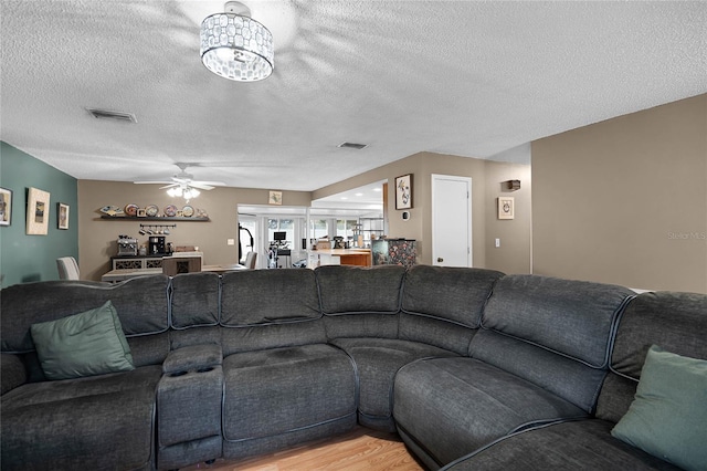 living room with ceiling fan with notable chandelier, a textured ceiling, and hardwood / wood-style flooring