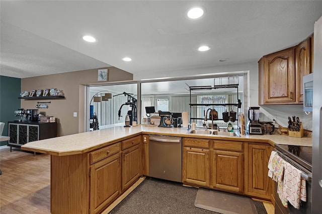 kitchen featuring kitchen peninsula, hardwood / wood-style flooring, sink, and appliances with stainless steel finishes