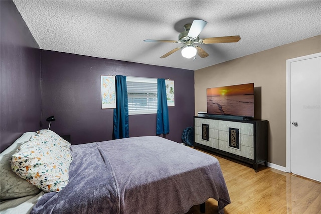 bedroom featuring ceiling fan, a textured ceiling, and light wood-type flooring