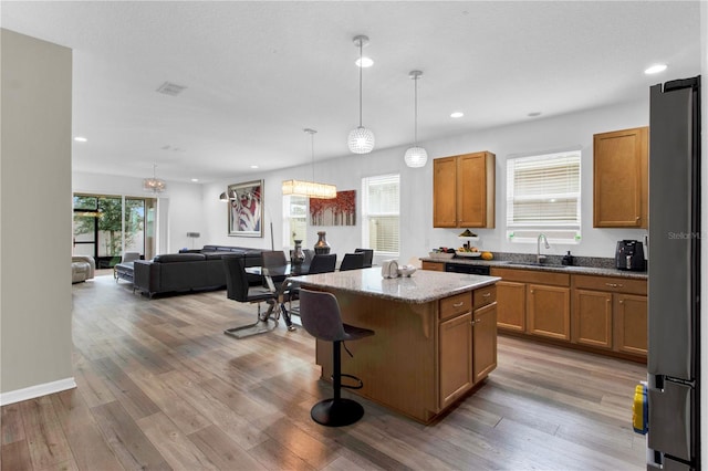 kitchen with a wealth of natural light, a breakfast bar, a kitchen island, and hanging light fixtures