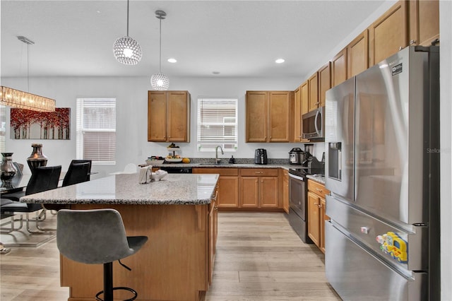 kitchen featuring appliances with stainless steel finishes, a center island, decorative light fixtures, and plenty of natural light