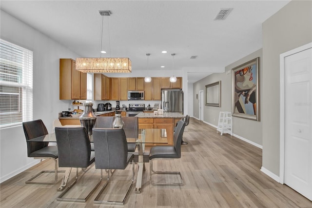 dining space with light hardwood / wood-style floors and a notable chandelier